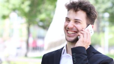 Şehirde telefonda konuşurken gülümseyen iş adamı 