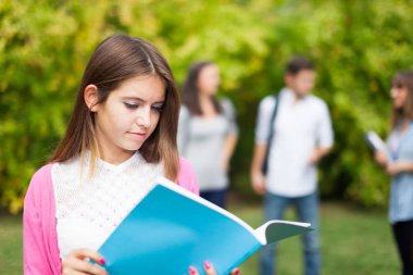 Açık bir grup öğrencinin önünde gülümseyen genç bir öğrenci portresi