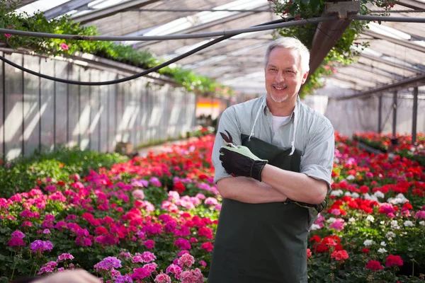 温室の花でいっぱいの笑みを浮かべて労働者の肖像 — ストック写真