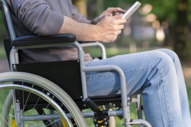 Bir tablet bir parkta kullanan bir Engelli adam detay