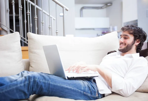 Man Met Een Laptopcomputer Terwijl Liggen Bank Zijn Huiskamer — Stockfoto