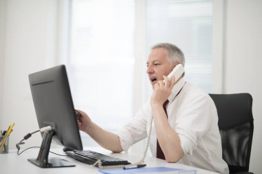 Onun masaüstü bilgisayar kullanırken telefonda konuşurken işadamı