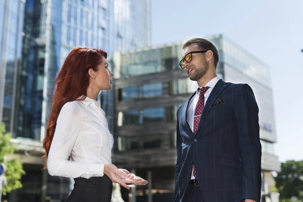 Businessman and businesswoman speaking in a city street
