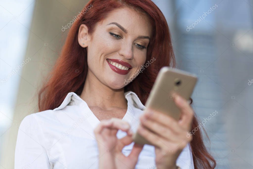 Portrait of a beautiful smiling woman using a mobile phone outdoors