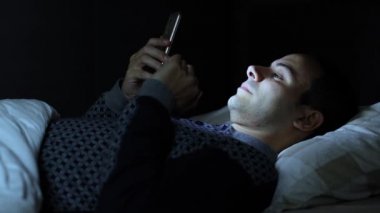 Yatakta 4 k onun cep telefonu kullanan adam