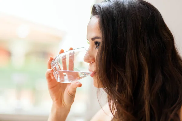 Beautiful young lady drinking water in restaurant