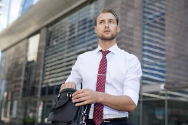 Bir elektronik cihaz üzerinden çantasını alarak iş adamı