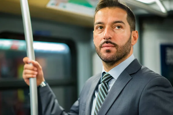 Businessman hanging to a pole in a train in the subway