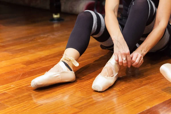 Classical dancer adjusting her shoes