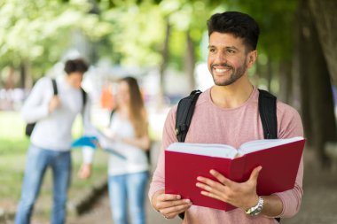 Mutlu erkek öğrenci gülümseyen, kitap okumak