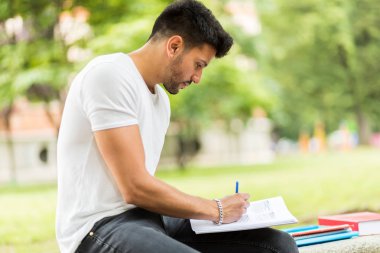 Yakışıklı genç adam parkta bankta ödev