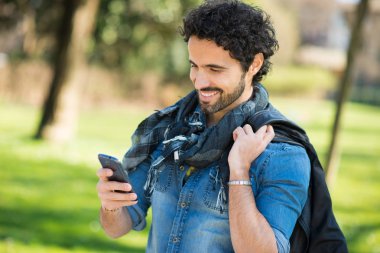 Cep telefonunu bir parkta kullanan bir adam portresi
