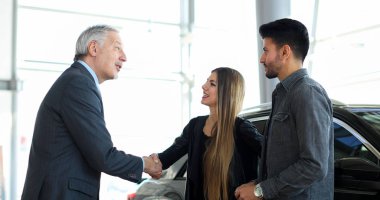 Genç bir çift için bir el sıkışma vererek araba satıcısı