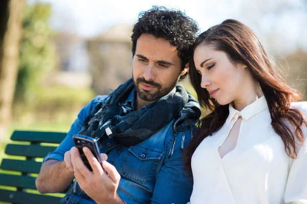 Hombre Sonriente Mostrando Teléfono Móvil Una Chica Parque —  Fotos de Stock