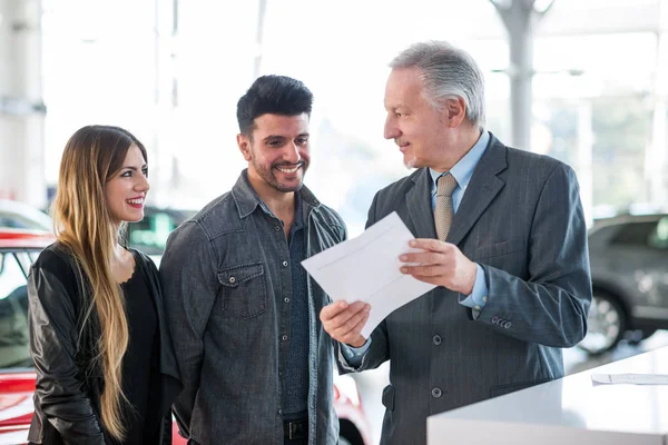 Happy Young Family Talking Salesman Car Showroom — Stock Photo, Image