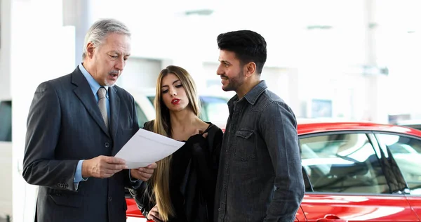 Car Dealer Reading Contract Couple Auto Showroom — Stock Photo, Image