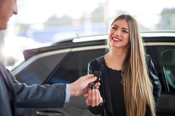 ショールームで彼女の車のキーを取る女性 — ストック写真