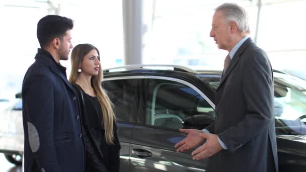 汽车经销商向一对夫妇展示一辆汽车4K — 图库视频影像