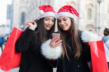 Kadın bir cep telefonu bir şey arkadaşıyla Milano'da alışveriş yaparken gösterir