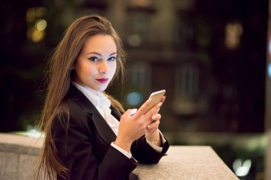 Bir şehirde gece cep telefonunu kullanan kadın