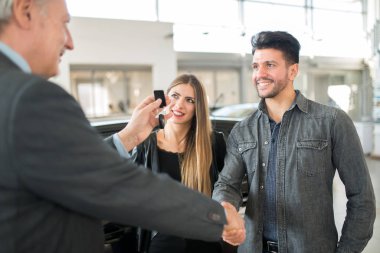 Yeni arabası için anlaşma imzalamaya bir el sıkışma veren ve anahtarları veren adam