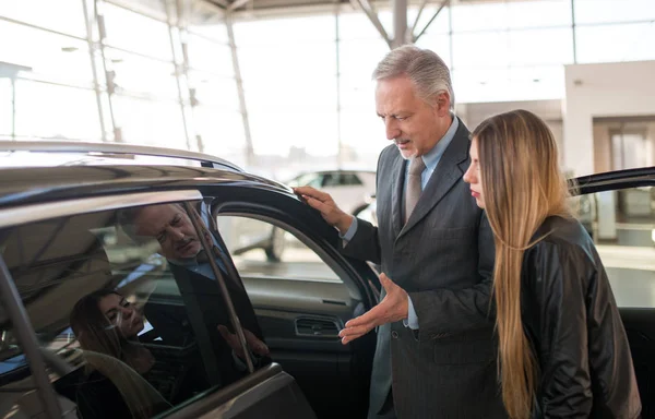 ショールームで新しい車を買うためにセールスマンと話す女性 — ストック写真