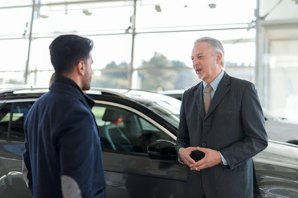 Jovem Conversando Com Vendedor Escolhendo Seu Novo Carro Showroom — Fotografia de Stock