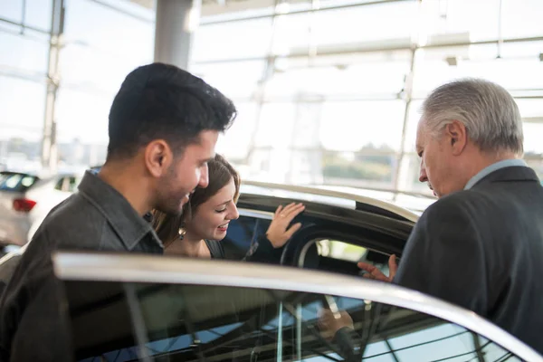 Szczęśliwa Młoda Rodzina Rozmawia Sprzedawcą Wybiera Nowy Samochód Salonie — Zdjęcie stockowe