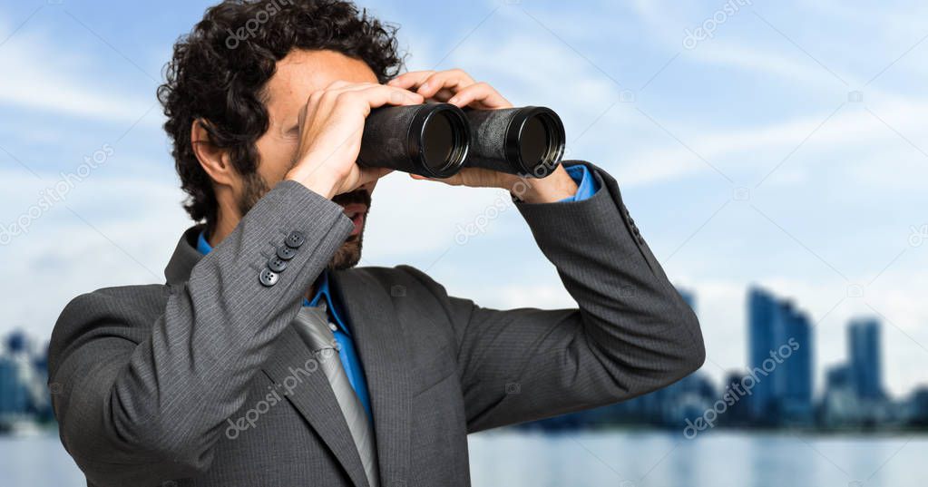 Businessman looking through binoculars