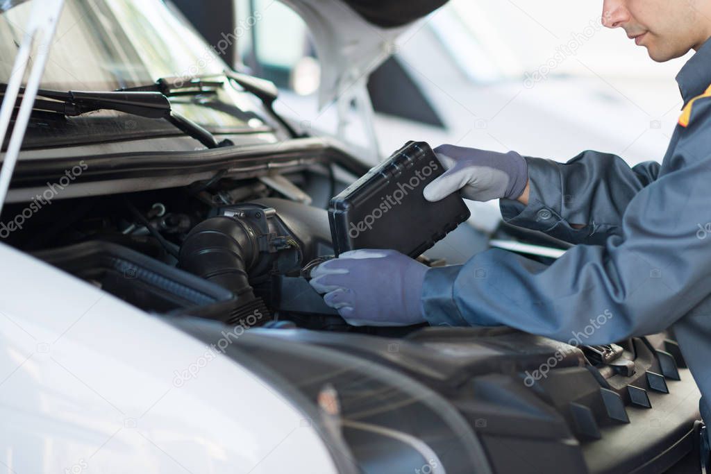 Car mechanic putting oil in a van engine