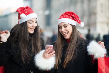 Birlikte bir fotoğraf çekimi Noel şapka genç kadınlarda gülümseyen