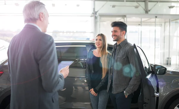 couple choosing car in saloon with a car dealer