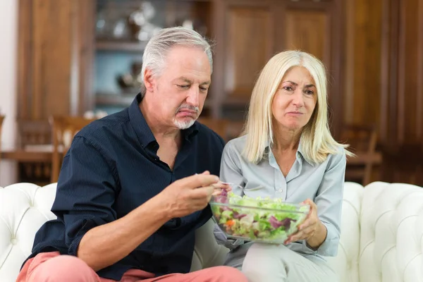 Disgusted couple eating salad at home