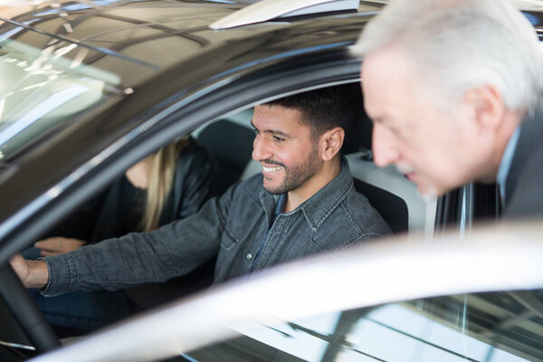 пара, выбирающая автомобиль в салоне с автодилером
