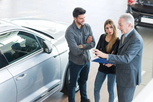 Feliz Jovem Família Conversando Com Vendedor Escolhendo Seu Novo Carro — Fotografia de Stock