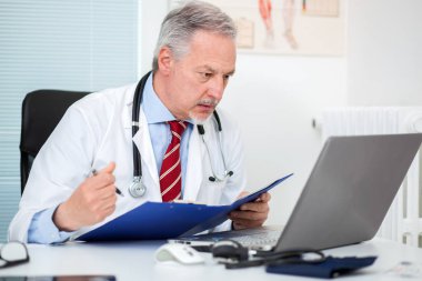 Başhekim stüdyosunda dizüstü bilgisayarında çalışıyor.