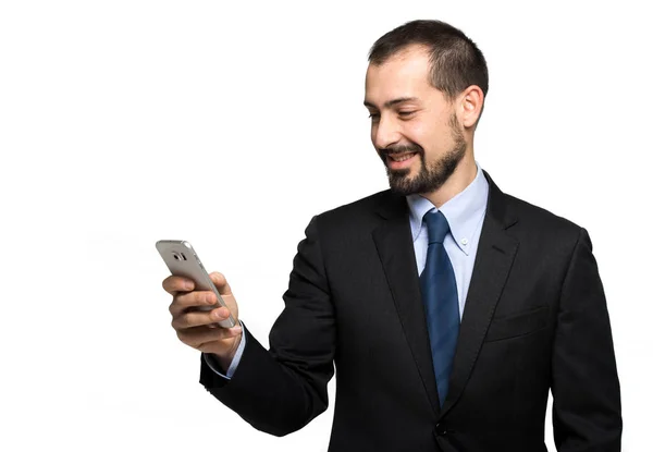 英俊的商人在他的智能手机上阅读消息 孤立在白色的背景 — 图库照片