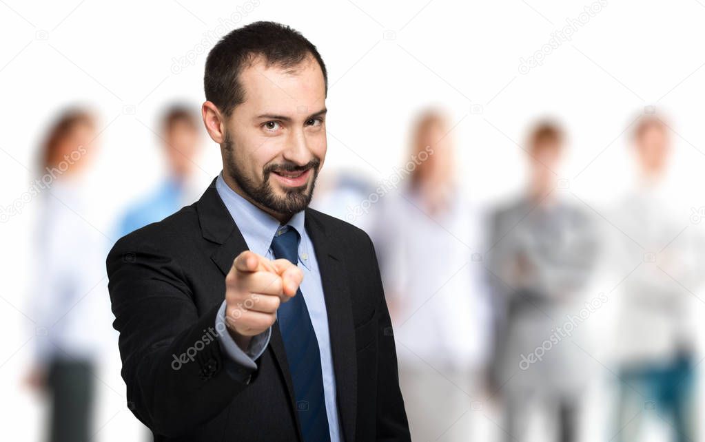 Portrait of handsome businessman pointing at camera in front of team  