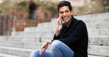 Açık merdivenlerde oturan telefonda konuşan genç adam