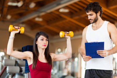 Woman lifting dumbbells with instructor clipart