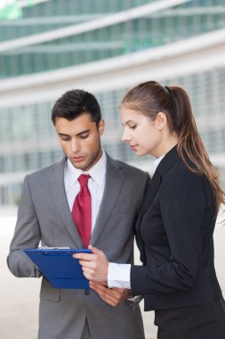 Bir belgeyi okuyan genç iş adamları