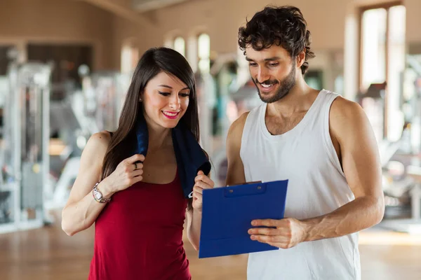 Jonge Vrouw Praten Met Haar Fitnesstrainer Sportschool Als Een Klembord — Stockfoto