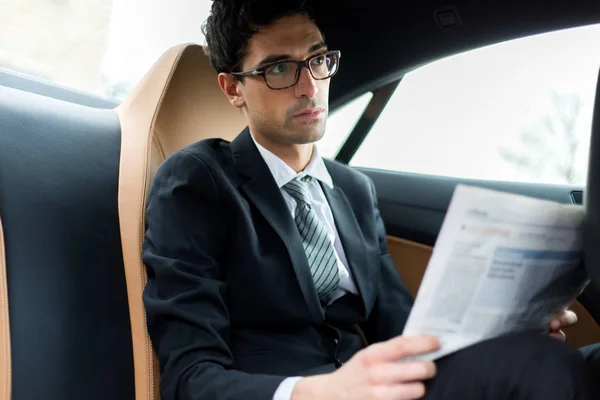 車の後部座席で新聞を読んでいる若いマネージャー — ストック写真