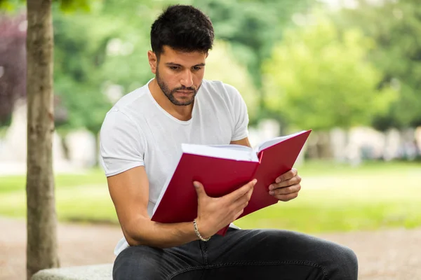 Pohledný Mladý Muž Čtení Knihy Lavičce Parku — Stock fotografie