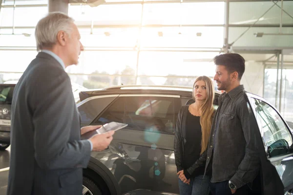 Feliz Joven Familia Hablando Con Vendedor Elección Nuevo Coche Una —  Fotos de Stock