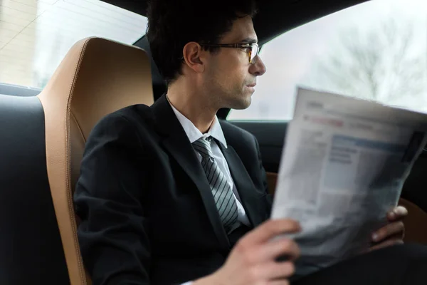 年轻的经理在汽车后座上看报纸 — 图库照片