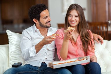 Çift pizza yemek ve Tv izlerken