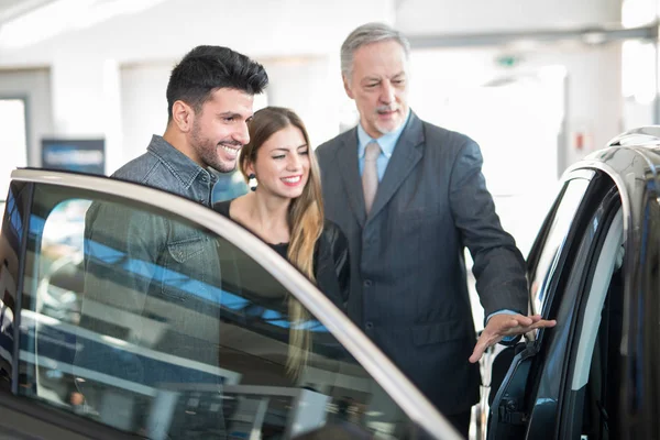 Feliz Jovem Família Conversando Com Vendedor Escolhendo Seu Novo Carro — Fotografia de Stock
