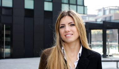 modern bir kentsel ortamda açık havada gülümseyen genç kadın yönetici