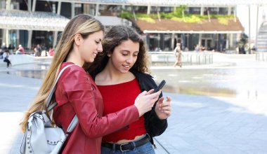İki mutlu kadın arkadaş bir akıllı telefon açık bakıyor